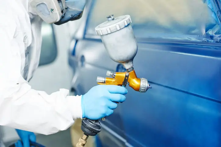 Carolina Collision and Frame Service | Auto body paint technician wearing safety goggles and a mask painting a car blue