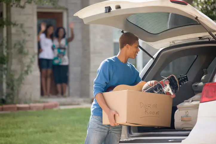 Carolina Collision and Frame Service | Mother and sister waving to a young boy heading off to college and loading a box into the back of his car