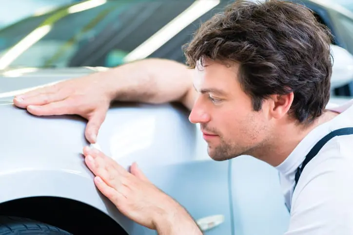 Carolina Collision and Frame Service | Auto body technician inspecting the repair work of a white car up close